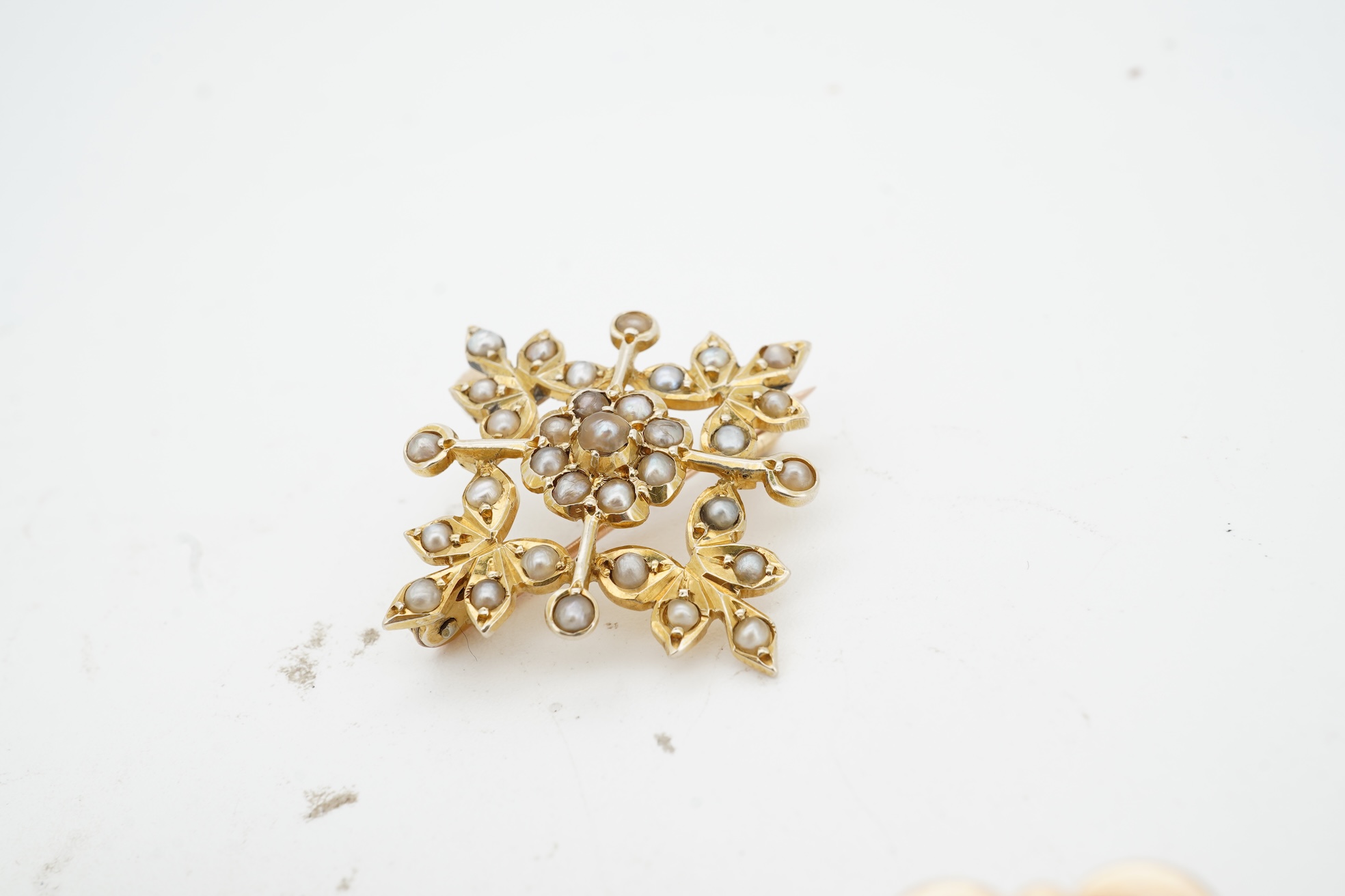 Three brooches, comprising: a Victorian circular brooch centring on a cabochon onyx set with a rose-cut diamond in a star setting, to concentring bands of seed pearls and Greek key motifs in black enamel, the reverse wit